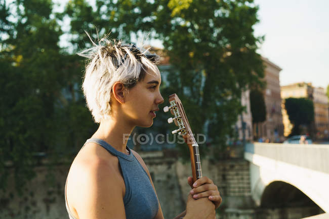 Дівчина грає на маленькій гітарі на вулиці — стокове фото