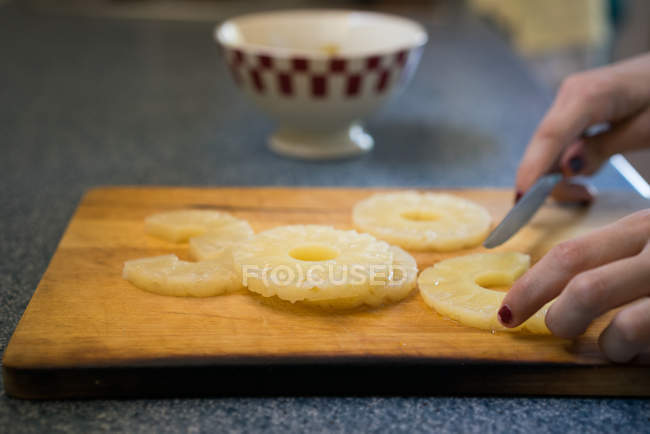 Crop woman cutting pineapple — Stock Photo
