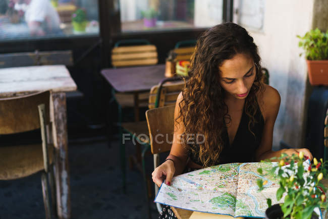 Chica en café mapa de lectura - foto de stock