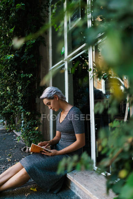 Woman reading book at window — Stock Photo