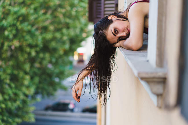 Giovane donna piegandosi fuori dalla finestra — Foto stock