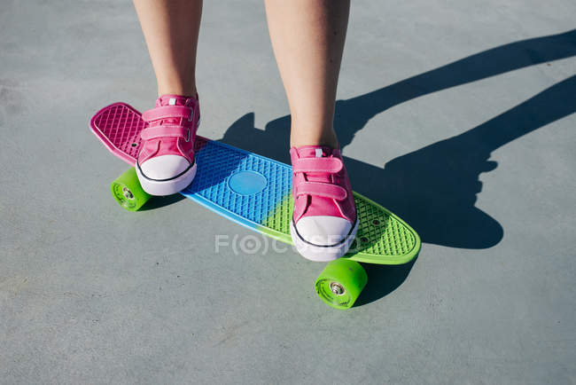Crop girl sur skateboard coloré — Photo de stock