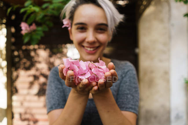 Frau bläst Blütenblätter aus den Händen — Stockfoto