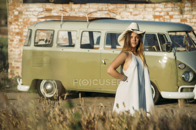 Chica en sombrero de vaquero posando sobre el fondo de furgoneta estacionada en la naturaleza - foto de stock
