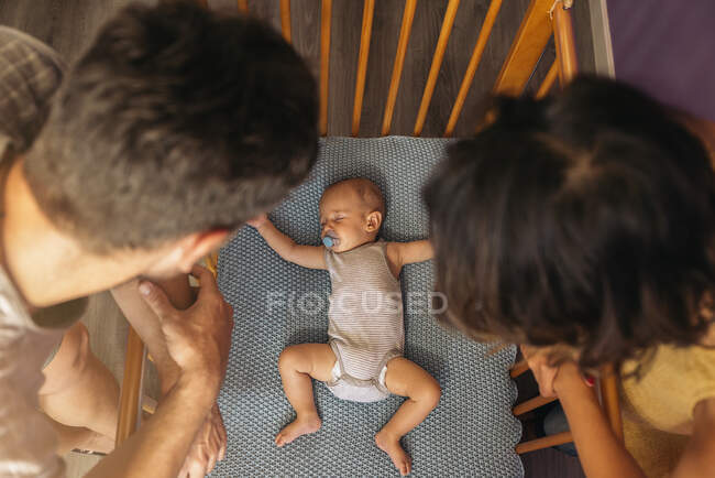 Vue aérienne de la mère et du père regardant bébé dormir dans un berceau — Photo de stock