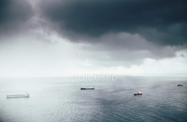 Groupe de navires naviguant sous un ciel gris lourd — Photo de stock