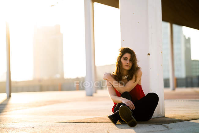 Junge Frau sitzt auf Asphalt und blickt in Kamera. — Stockfoto