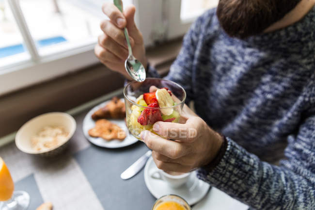 Зображення людини, що їсть фруктовий салат у їдальні — стокове фото