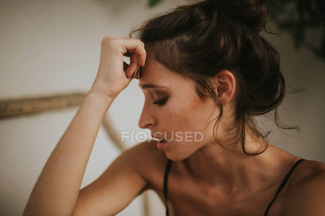 Young brunette with bare shoulders and hairstyle looking down — Stock Photo