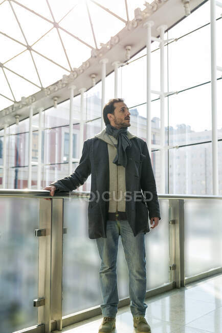 Young man at the station illuminated by the sunlight through the glass windo — Stock Photo