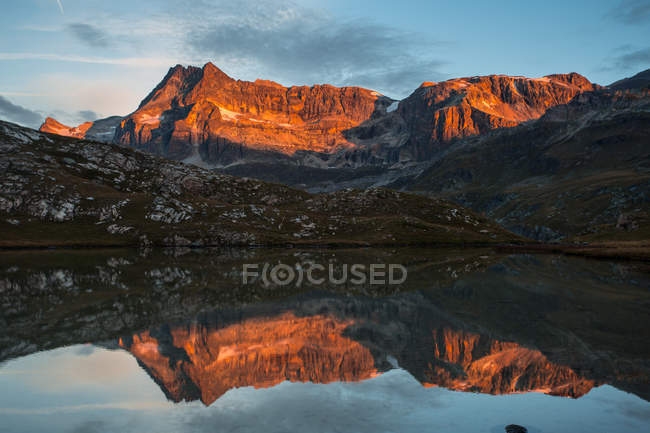 Lake surface reflecting sunlit mountains — Stock Photo