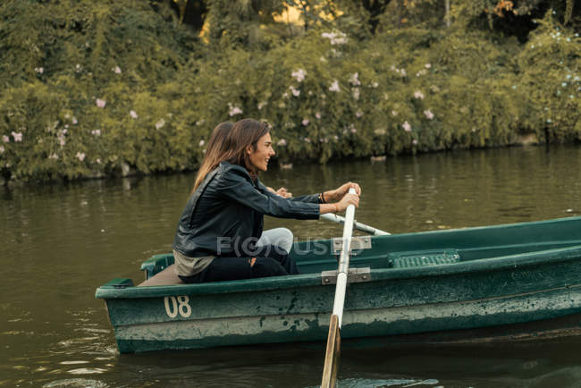 Vista laterale di coppia canottaggio insieme in barca al lago parco — Foto stock