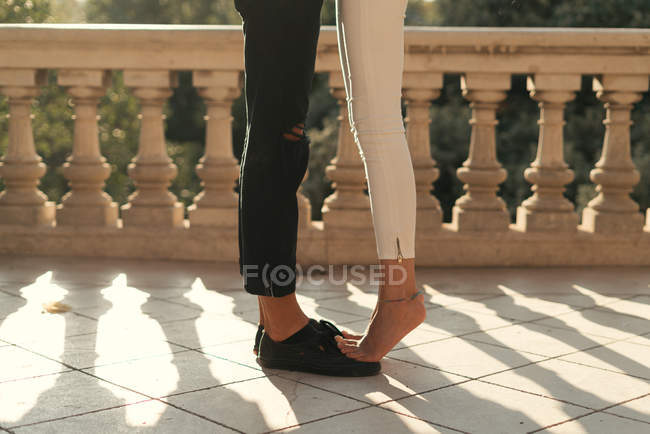 Crop of girlfriends legs standing foots on black boyfriends shoes . — Stock Photo