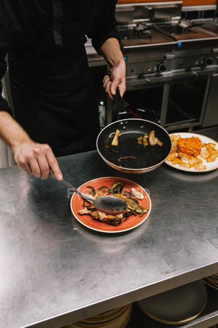 Середина кухаря, який подає страву на тарілці на кухні ресторану — стокове фото