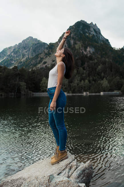 Mujer de pie sobre piedra en el lago - foto de stock