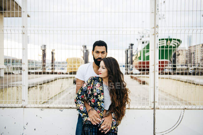Hombre abrazando chica sobre industrial muelle telón de fondo - foto de stock