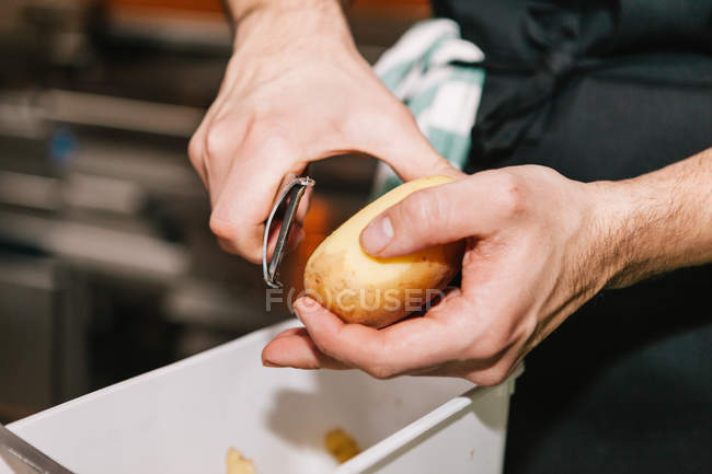 Vista da vicino delle mani maschili pelare la patata — Foto stock