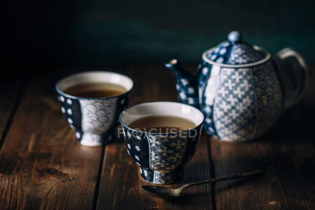 Ainda vida de xícaras de porcelana de chá quente e panela na mesa de madeira . — Fotografia de Stock