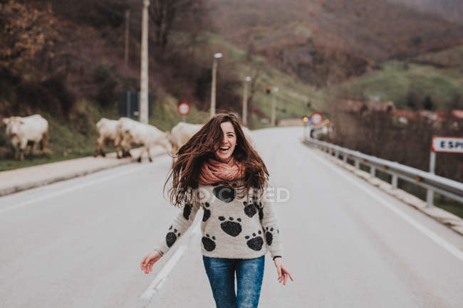 Cheerful girl with windy hair laughing on asphalt road in countryside — Stock Photo
