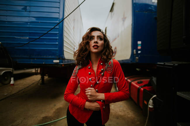 Mulher de casaco vermelho posando entre reboques — Fotografia de Stock