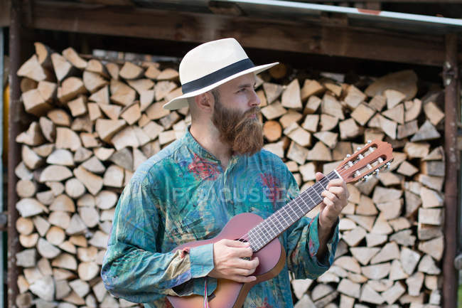 Barbuto uomo in cappello giocare ukulele — Foto stock