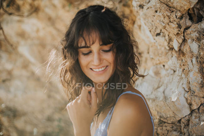Портрет ніжної брюнетки дівчина посміхається і дивиться вниз над поверхнею пісковика — стокове фото