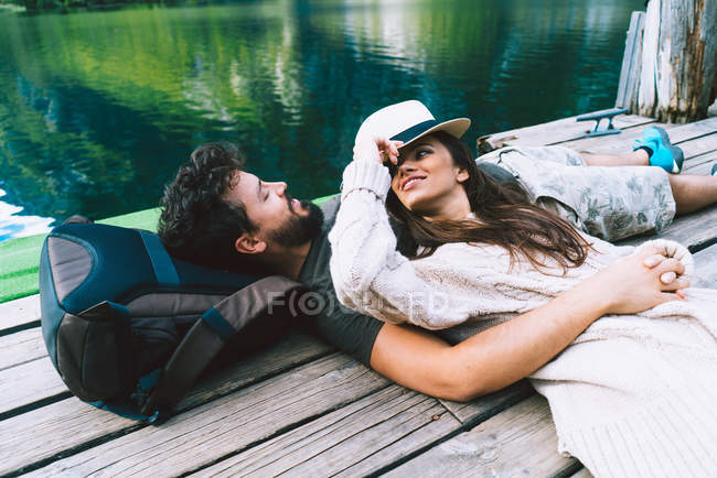 Couple couché sur une jetée en bois au lac — Photo de stock