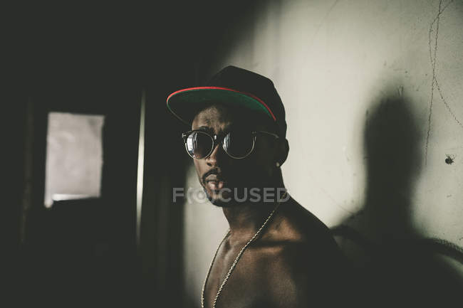Hombre seguro en gafas de sol posando en habitación abandonada . - foto de stock