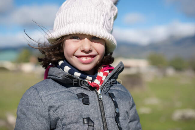 Primer plano de una niña pequeña con gorra de lana y bufanda en el campo - foto de stock