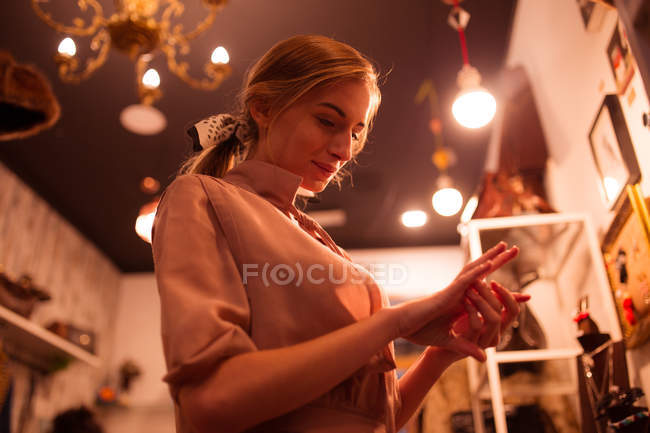 Young stylish girl looking at jewelry on hand at clothing room. — Stock Photo