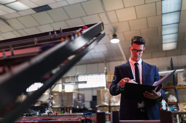 Formal man with folder checking conditions on factory — Stock Photo
