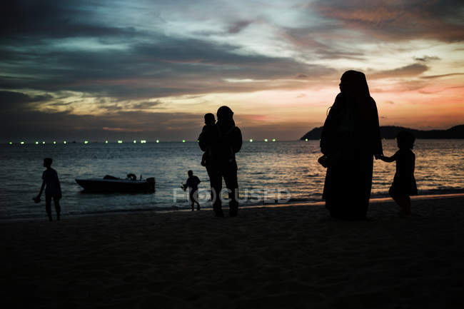 Malaysia - 1. Mai 2016: Silhouetten von Menschen mit Kindern am Strand über dem Himmel bei Sonnenuntergang im Hintergrund. — Stockfoto