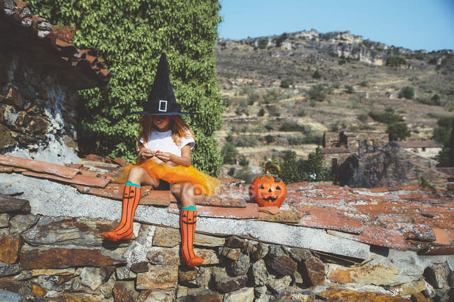 Menina em traje de Halloween sentado no telhado — Fotografia de Stock