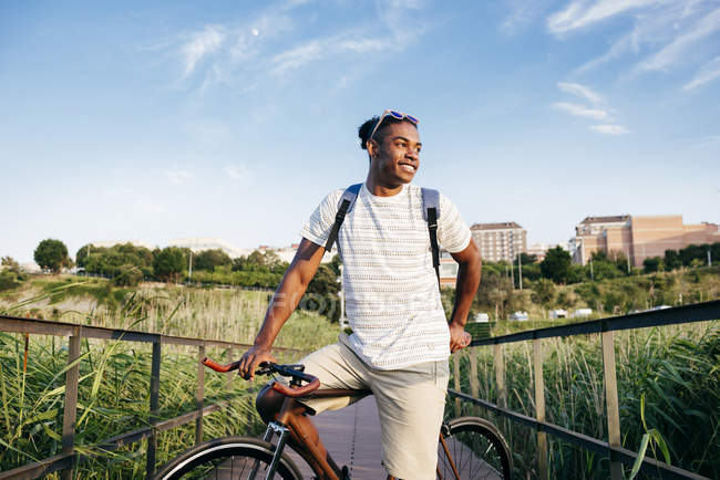 Man posing with bike on boardwalk — Stock Photo