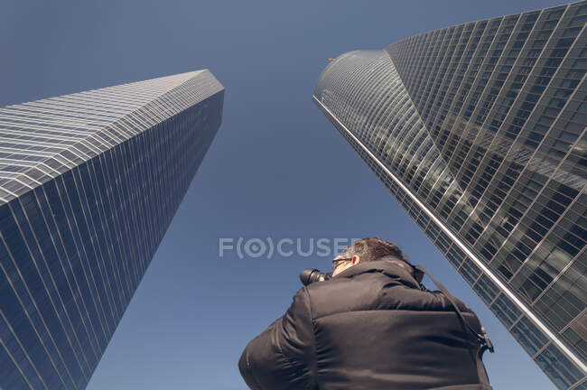 Homem tirando fotos de arranha-céus no centro financeiro — Fotografia de Stock