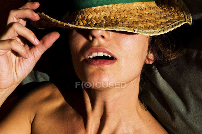 BARCELONA, ESPAÑA - 10 de julio de 2011: Mujer en sombrero de paja cubriendo los ojos posando a la luz del sol con la boca abierta . - foto de stock