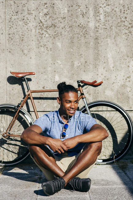 Улыбающийся мужчина сидит рядом с велосипедом — стоковое фото