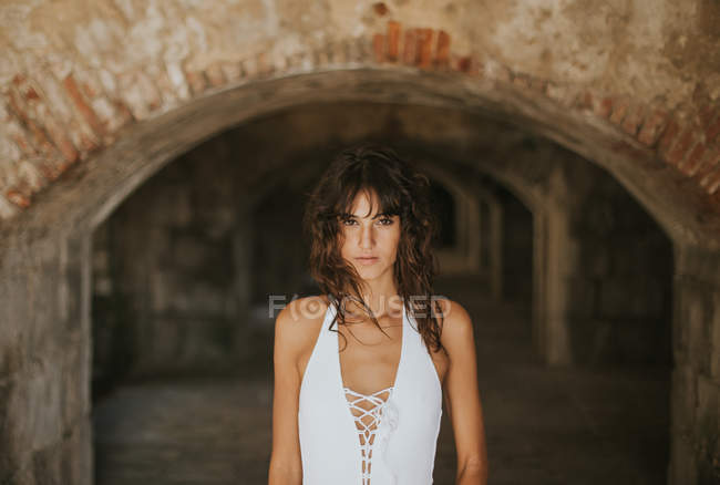 Portrait de femme brune posant dans une vieille cave abandonnée et regardant la caméra — Photo de stock