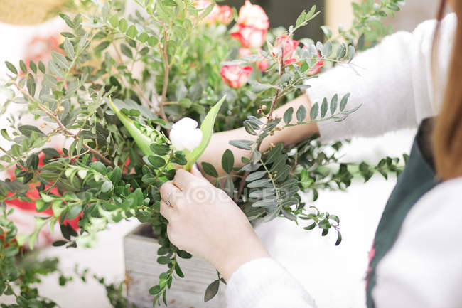 Primer plano de las manos femeninas haciendo arreglos florales en floristería - foto de stock