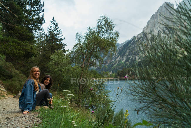 Cheerful women sitting at lake — Stock Photo