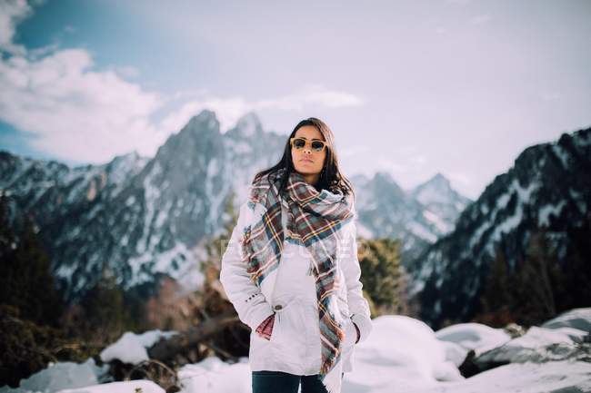 Brunette girl in sunglasses posing at snowy mountain landscape — Stock Photo