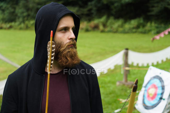 Homme barbu sérieux posant avec arc — Photo de stock