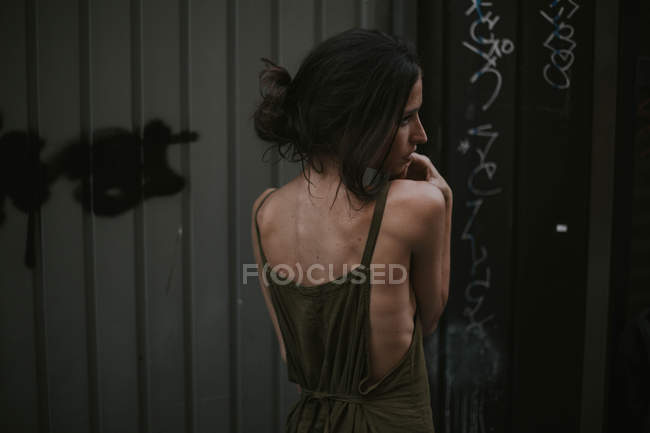 Rear view of young woman in khaki dress looking away — Stock Photo
