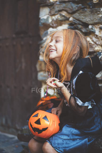 Girl with pumpkin basket sitting on bench — Stock Photo