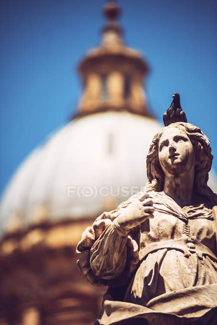 Ancient statue on background of blurred cayhedral — Stock Photo