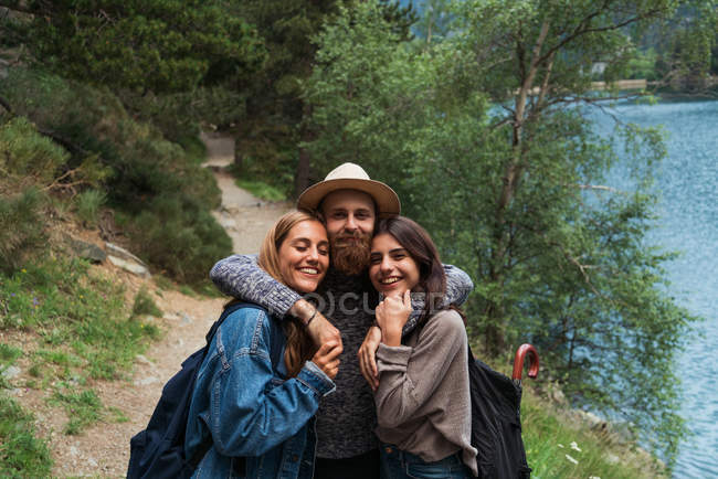 Tres amigos abrazos sobre el lago de montaña - foto de stock