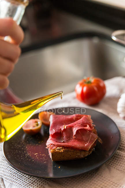 Person pouring oil on toast — Stock Photo