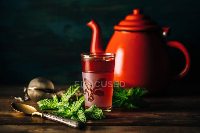 Verre à thé arabe rouge avec théière rouge sur table en bois . — Photo de stock