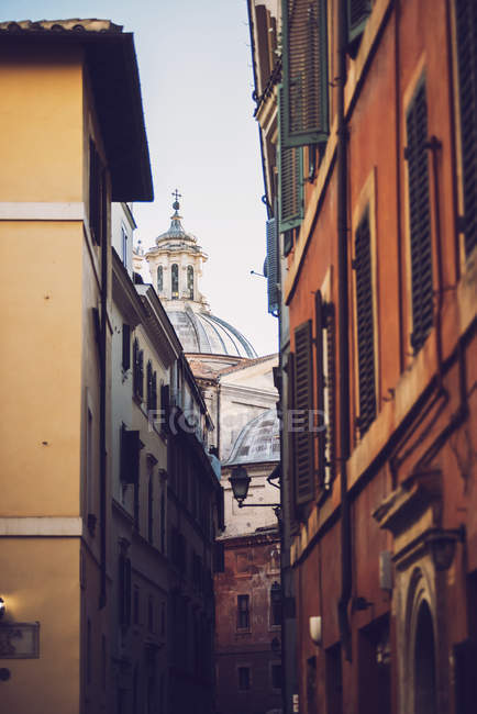 Bottom view of street buildings facade over ornate church dome on backdrop — Stock Photo