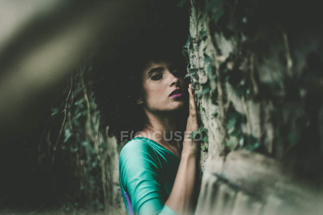 Portrait of sensual woman leaning on ivy-embraced wall — Stock Photo